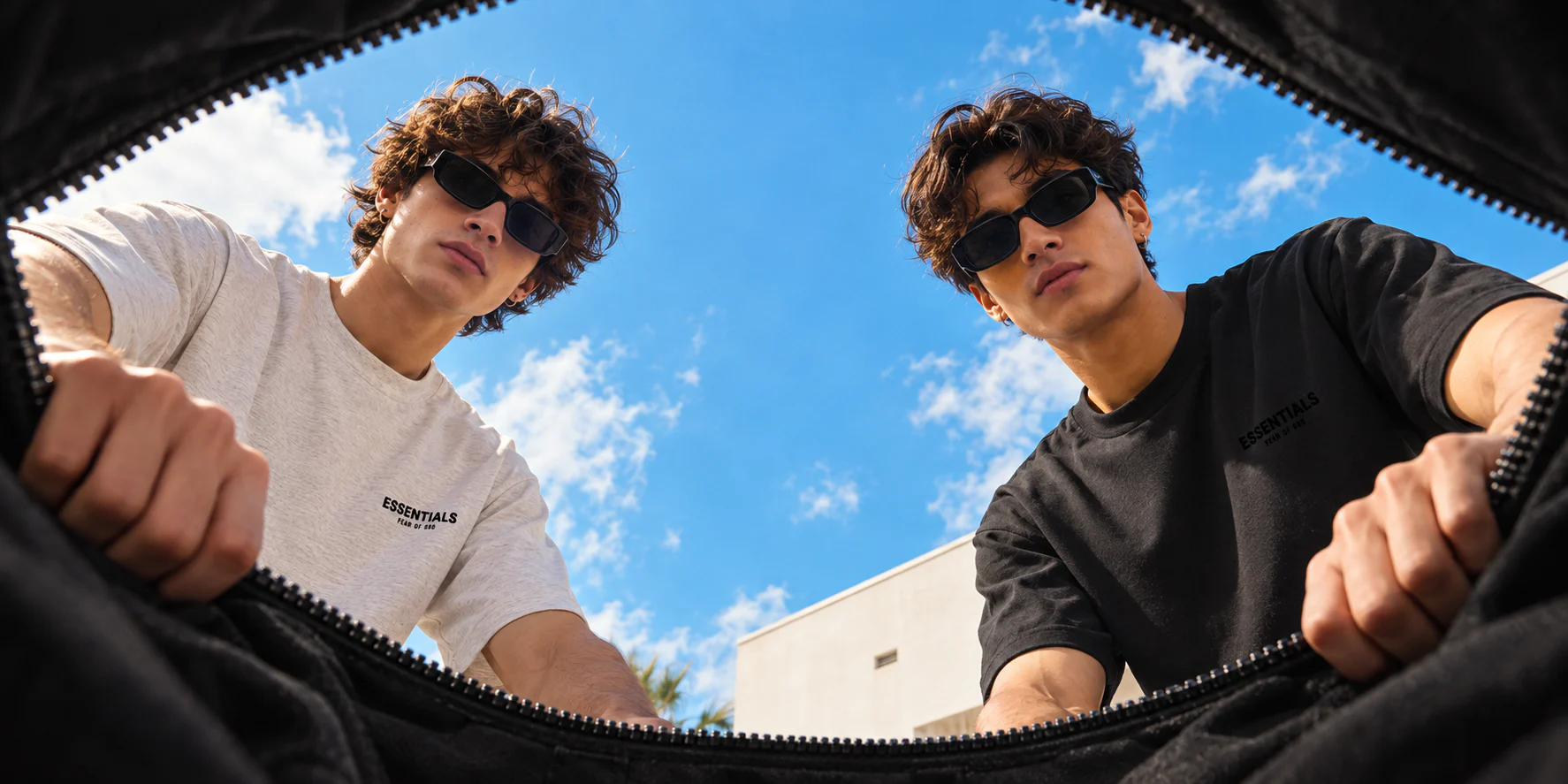 Dva muži v tričkách Fear of God Essentials se dívají do otevřené tašky