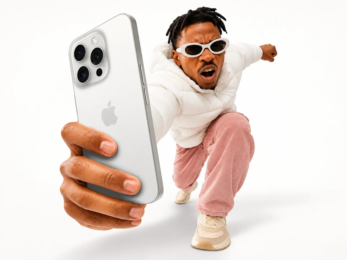 Muž v bílém streetwearu drží telefon směrem k fotoaparátu